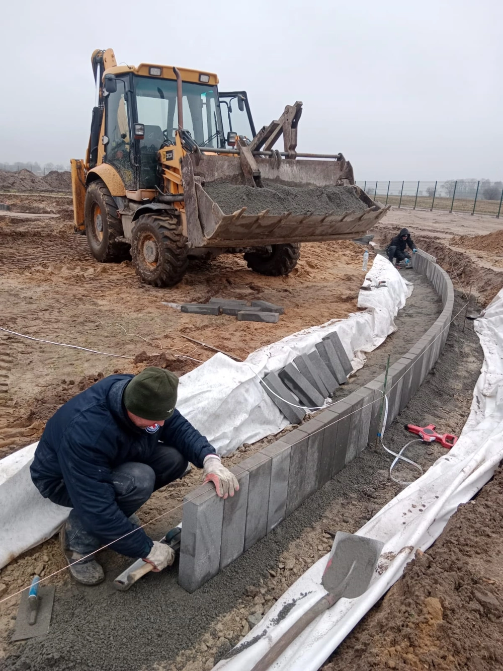 Układanie muru oporowego z betonowych bloczków w wykopie