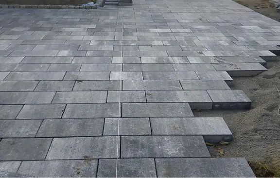 Układanie kostki brukowej z szarej kostki betonowej na przygotowanym podłożu