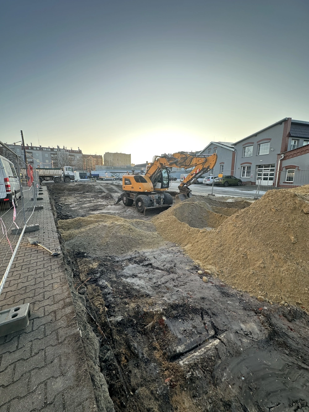 Koparka kołowa pracująca przy wykopach i hałdach ziemi na placu budowy – Usługi koparką